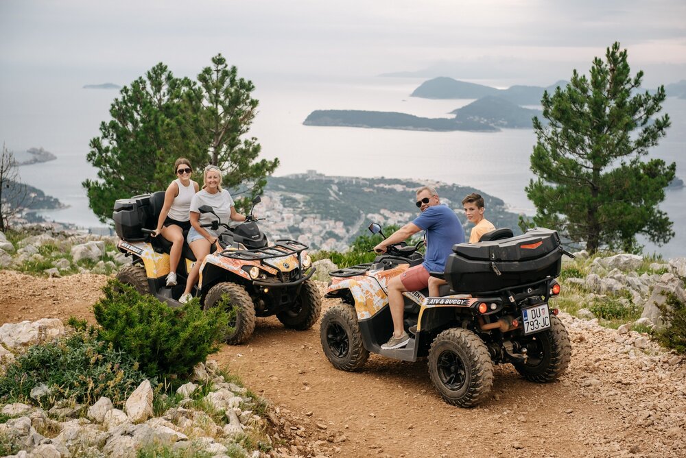 a family on a quad tour poses while the Elaphite Islands near Dubrovnik can be seen in the background